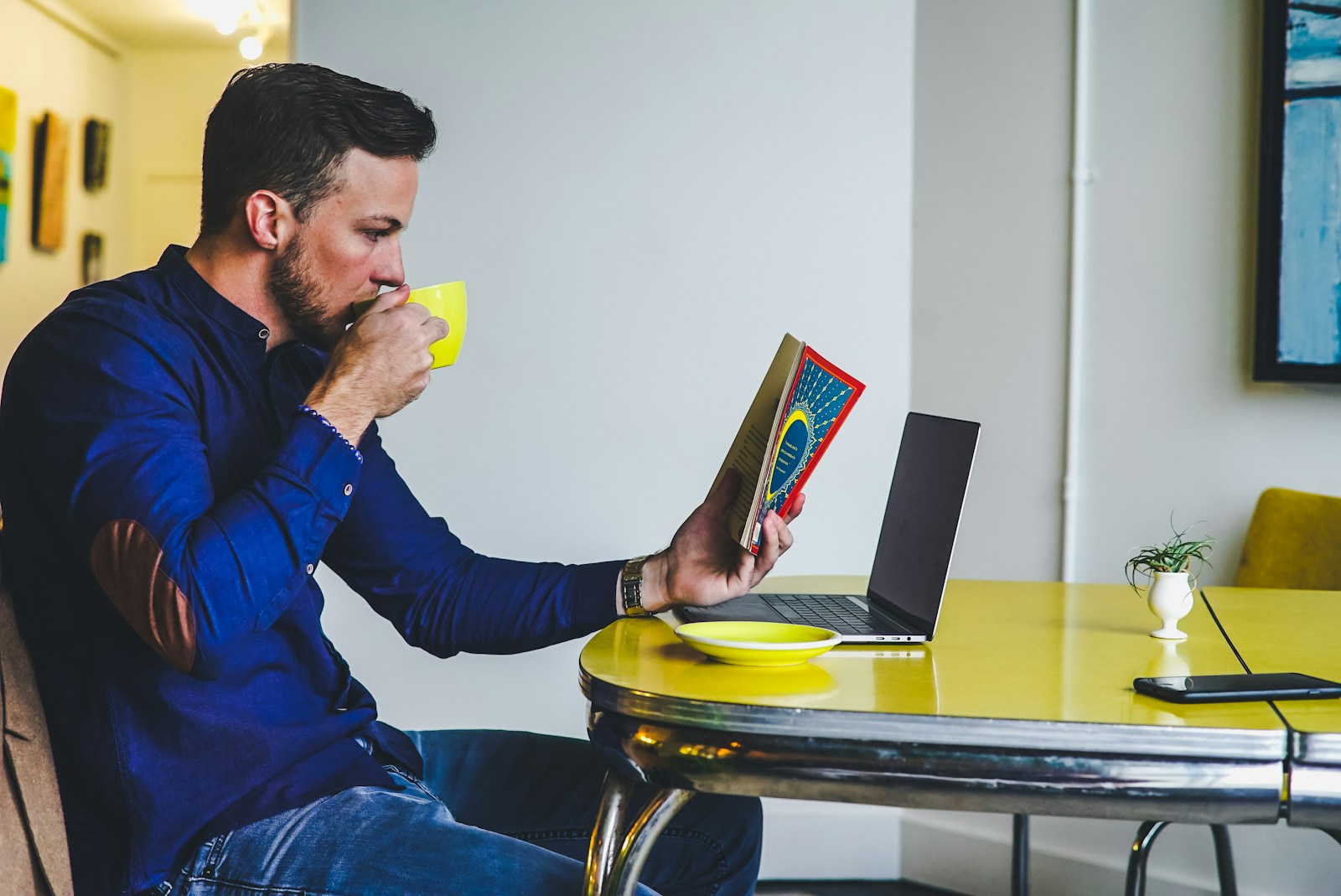 man drinking on yellow cup while reading book about the different types of coverage for your business