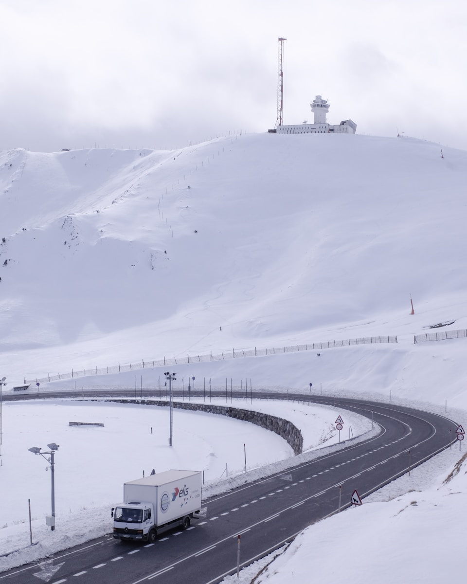 wide road with truck traveling under white sky